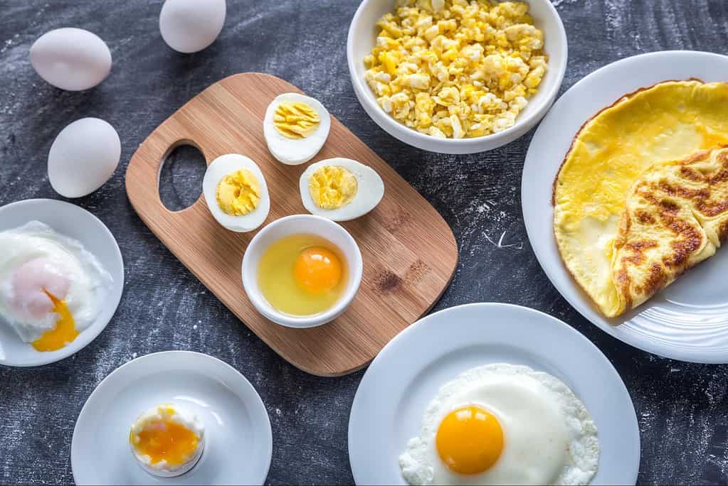 Fresh hard-boiled, fried, and soft eggs on plates and bowls.