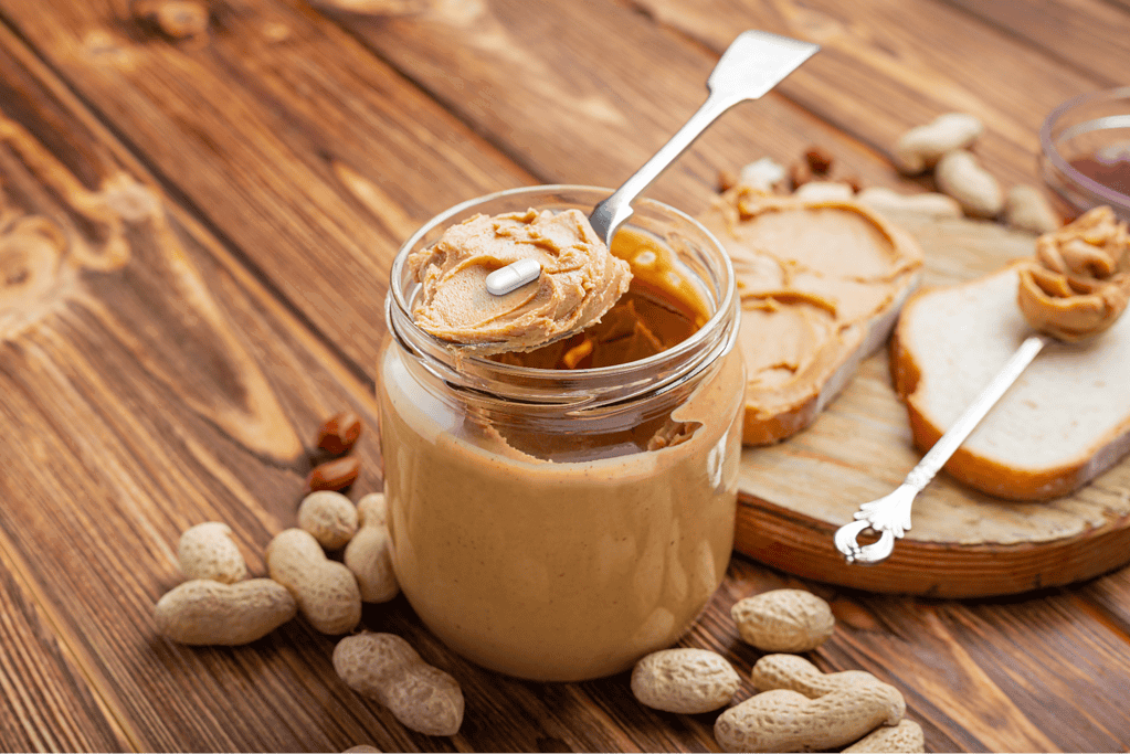 Peanut butter with a pill on a spoon, natural, healthy treat for dogs, on a wooden table.