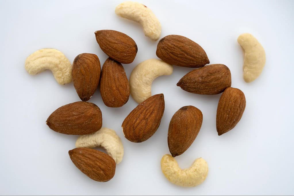 Close-up of almonds, cashews, and hazelnuts on white background for healthy snack concept.
