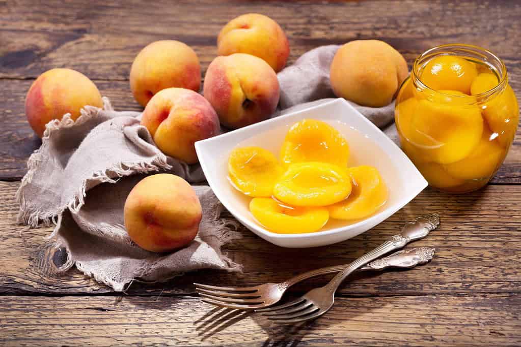Fresh peaches and peach preserves in a bowl, ideal for healthy snacks and desserts.