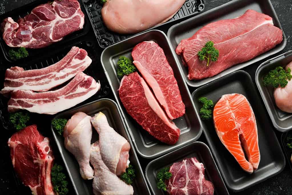 Assorted fresh meats displayed on black trays, suitable for dog nutrition and pet health.