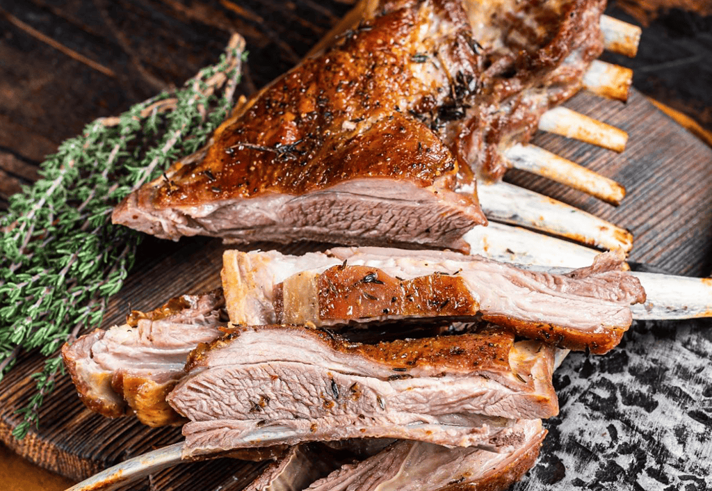 Delicious roasted lamb on a wooden board with herbs, perfect for dog and pet nutrition.