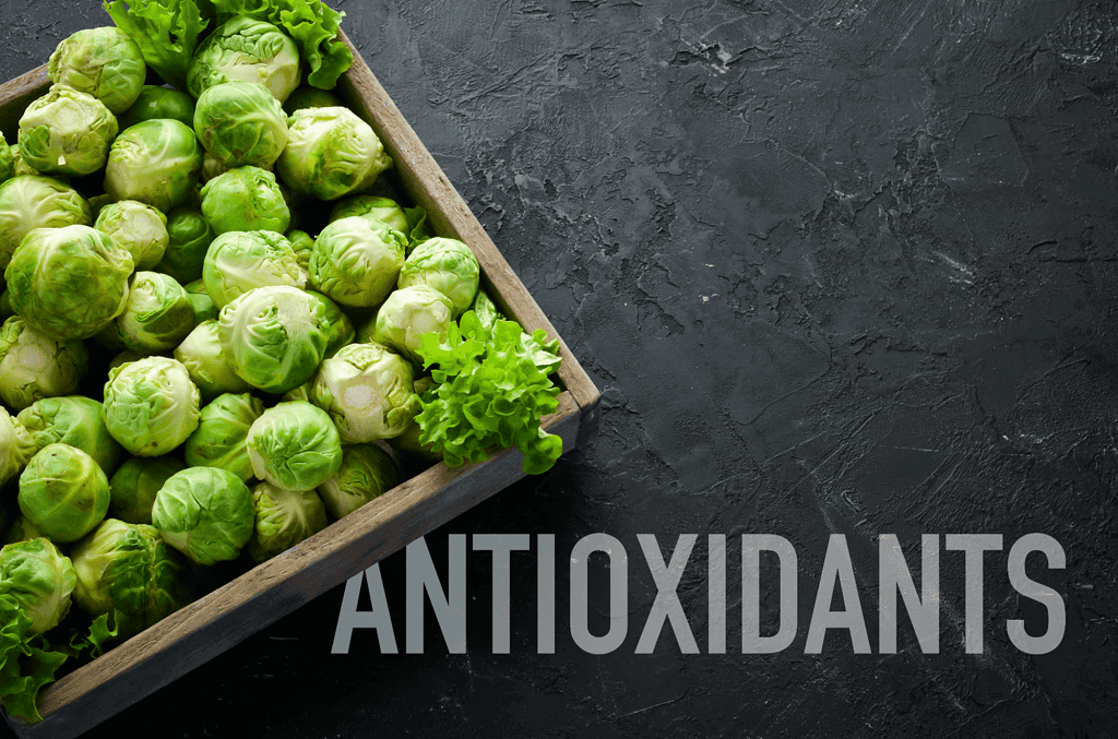 Fresh green Brussels sprouts with a leafy garnish on black textured background.