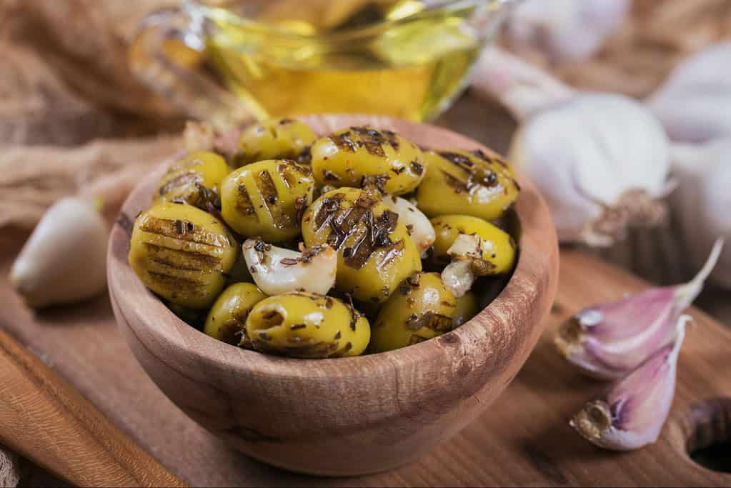 Delicious green olives marinated with garlic, herbs, and olive oil, perfect for snacks or appetizers.