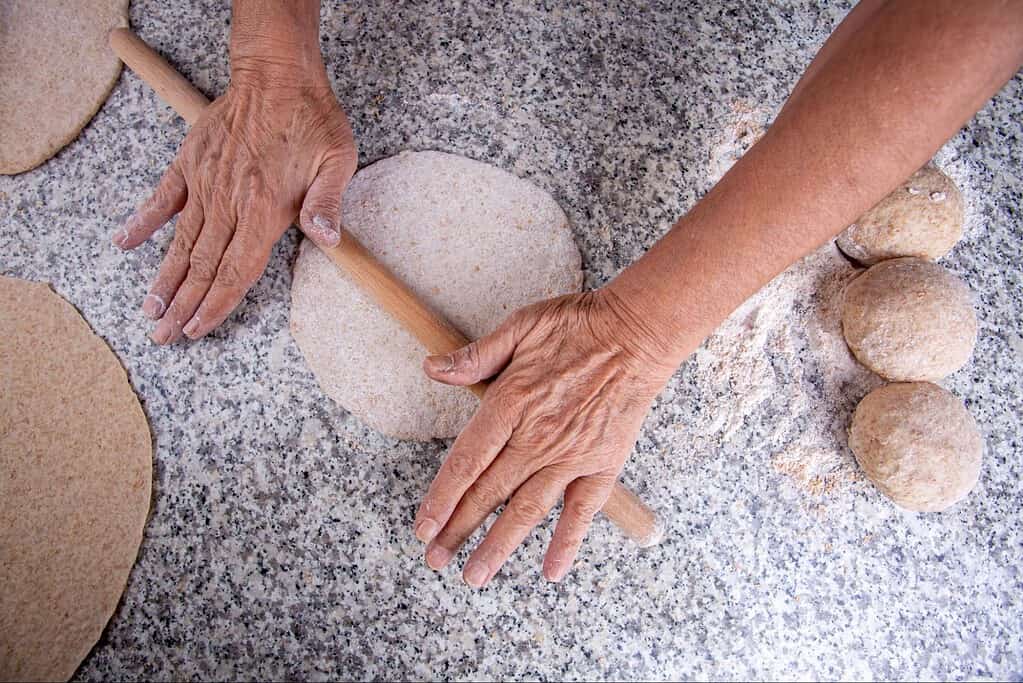 Hands shaping stones using rolling pin for DIY stone work.