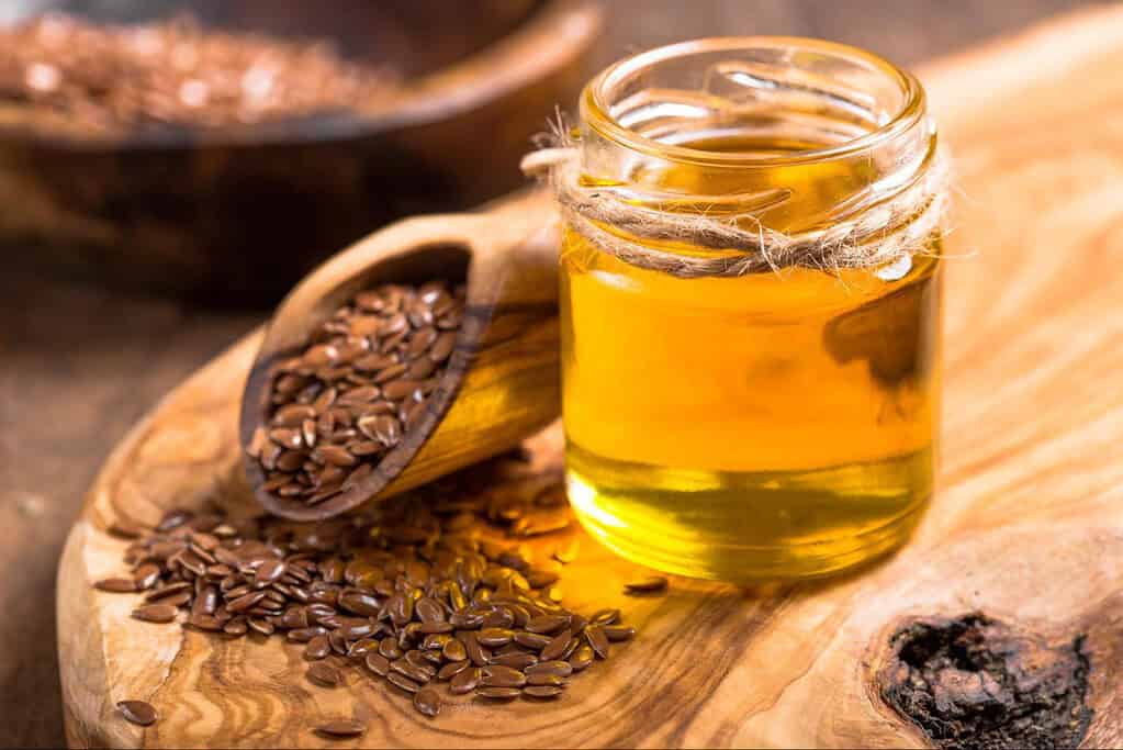 Healthy flaxseed oil in a glass jar on a rustic wooden surface.