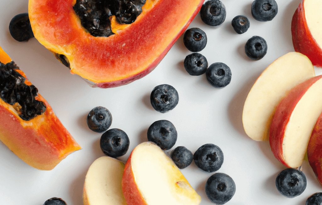 Fresh papaya, apple slices, and blueberries on white background.