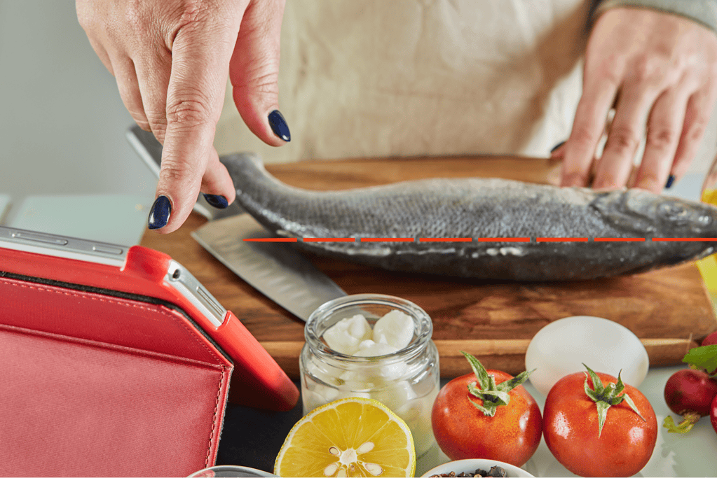 Highly detailed image of person preparing fresh fish on a kitchen counter, with tomatoes, lemon, and dairy.