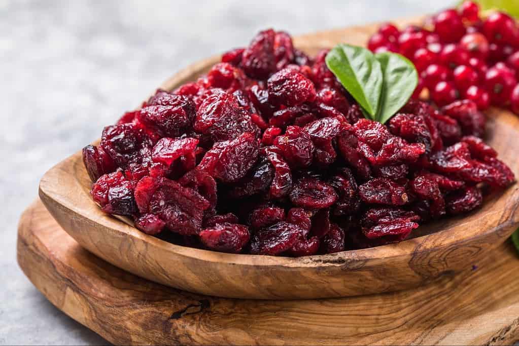 Vivid image of dried cranberries garnished with a basil leaf, perfect for healthy snacking.
