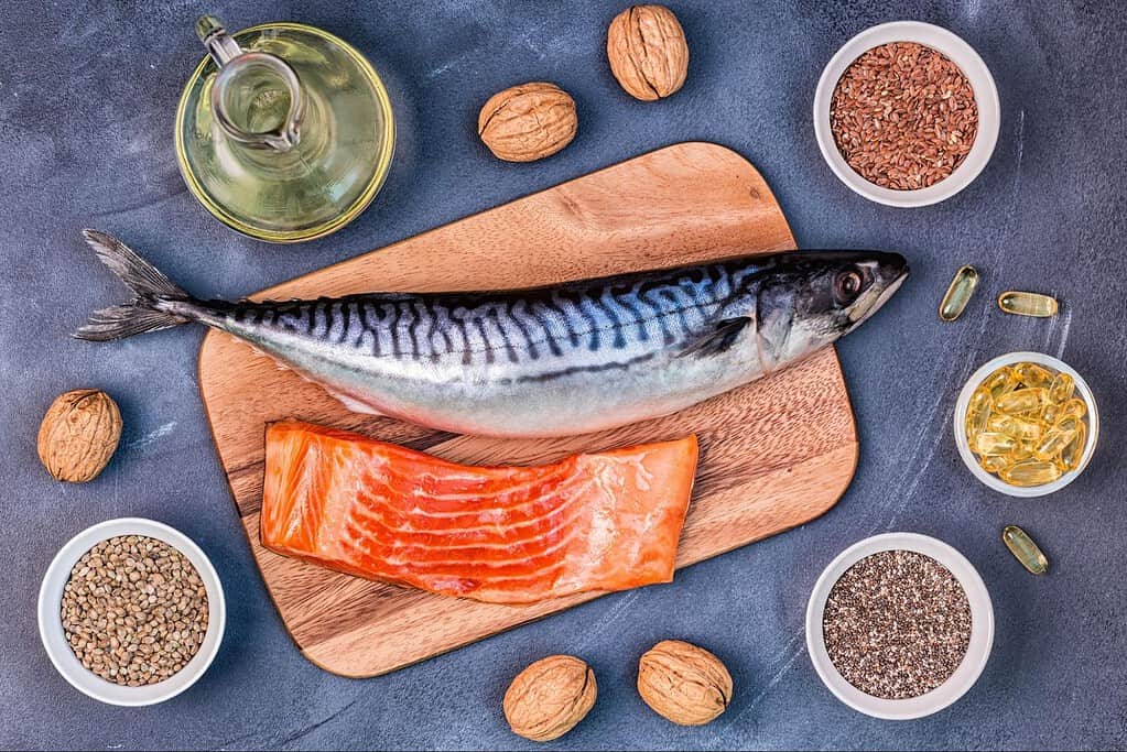 Fresh fish on wooden board with salmon, mackerel, oils, and seeds for healthy dog diets.