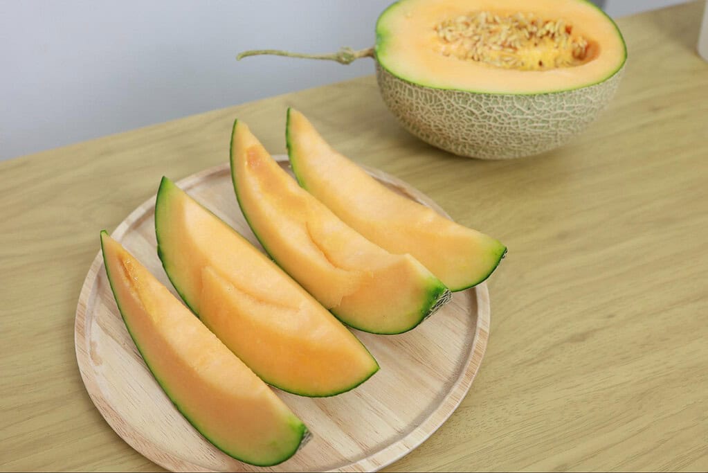 Fresh cantaloupe and melon slices on a wooden tray, ideal for healthy dog treats or fruit snacks.