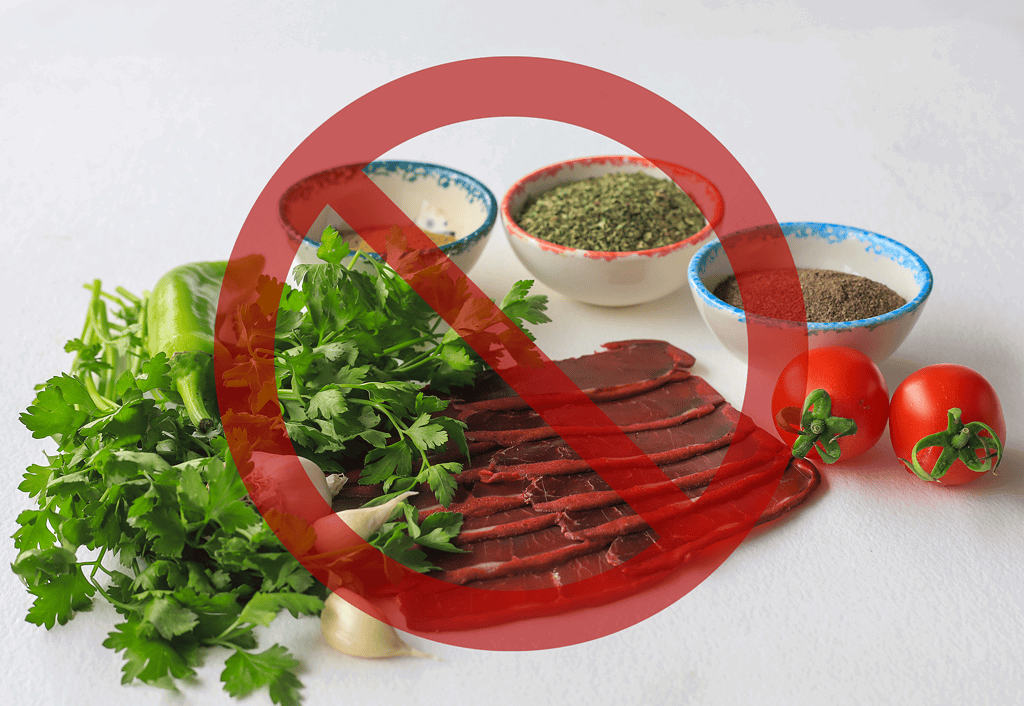 Fresh raw dog food ingredients with herbs, vegetables, and raw meat; not safe for dogs.