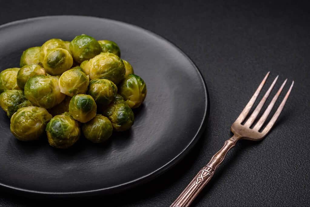 Fresh Brussels sprouts served on black plate, healthy vegetable side dish.