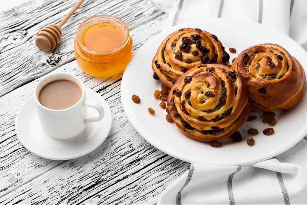 Delicious cinnamon rolls with raisins, honey, and coffee, perfect for breakfast or brunch.