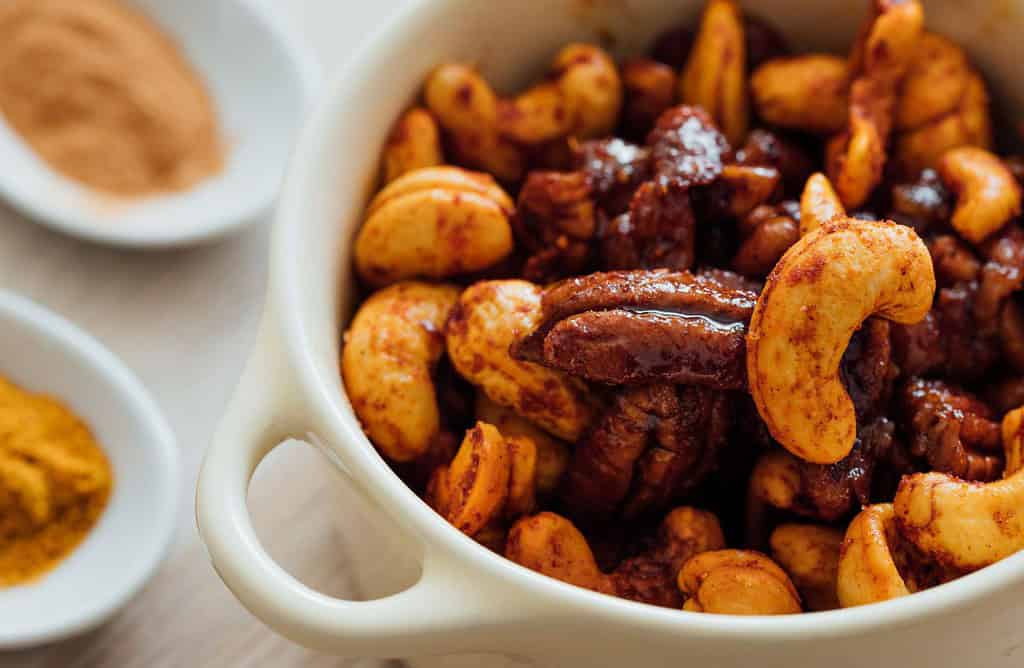 Delicious spiced roasted nuts in a white bowl, ideal snack for any occasion.