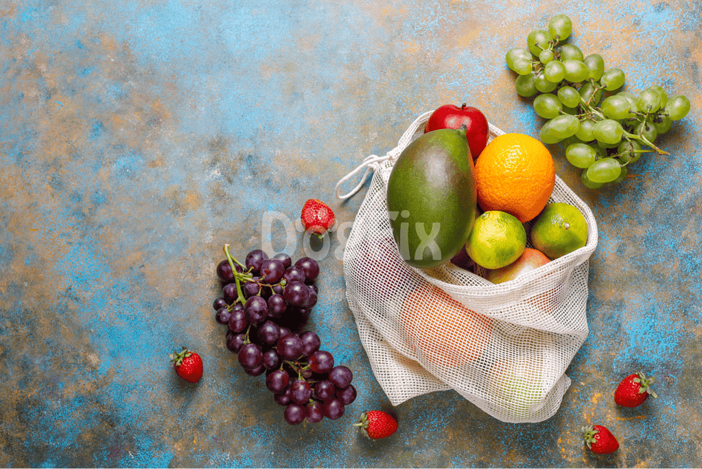 Organic fruits in a reusable bag on a textured surface, healthy snack options.