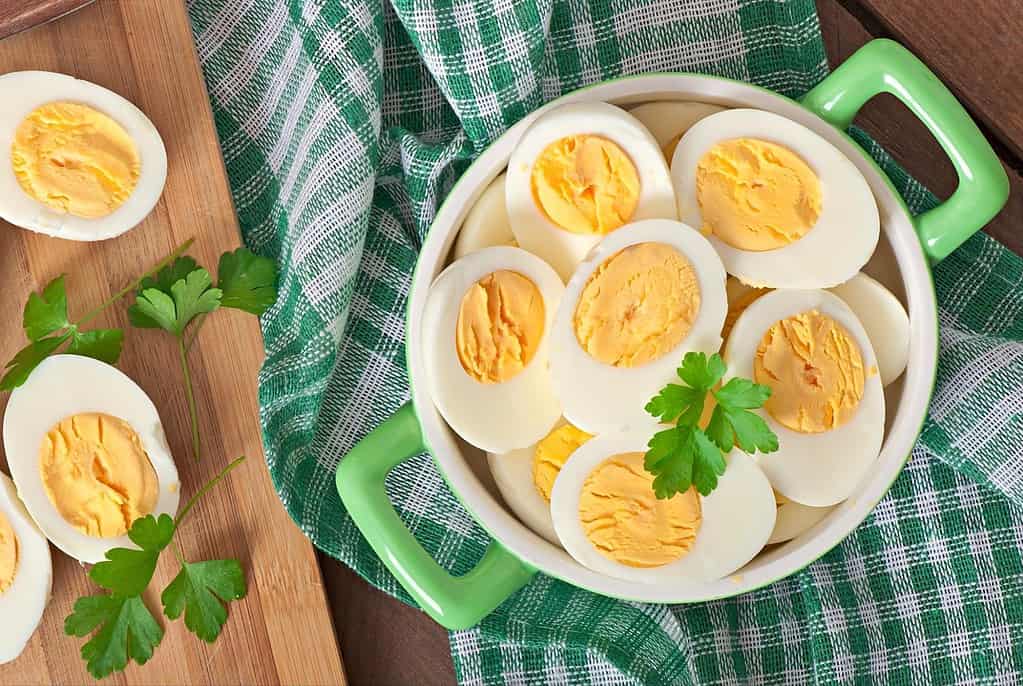 Alt text: Bowls of sliced and halved hard-boiled eggs garnished with parsley.