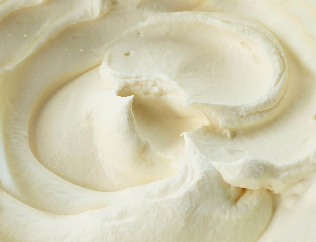 Close-up of creamy cheese spread with smooth texture and swirled appearance.