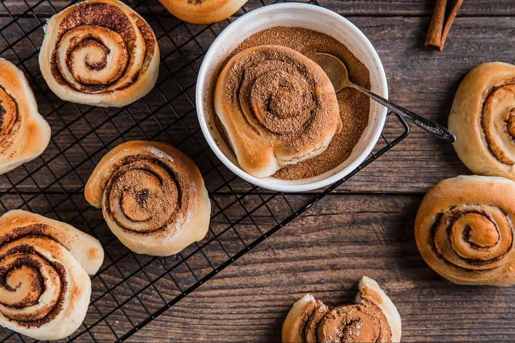 Delicious cinnamon rolls topped with sugar and cinnamon on a rustic wooden table.