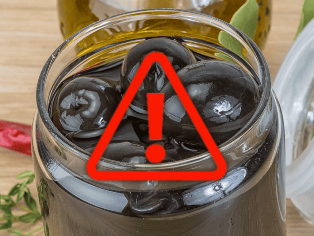 Bright red warning icon over jar of black olives with a warning symbol.