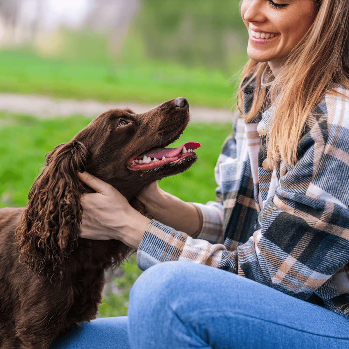 Happy woman holding her loyal dog outdoors, emphasizing dog love and pet wellbeing.