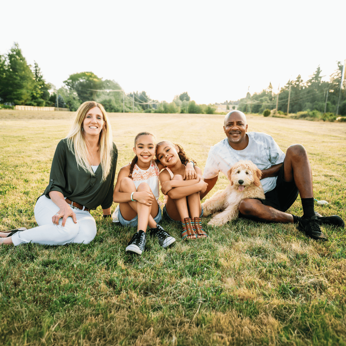 A joyful family enjoying outdoor quality time with their pet dog in a sunny park.