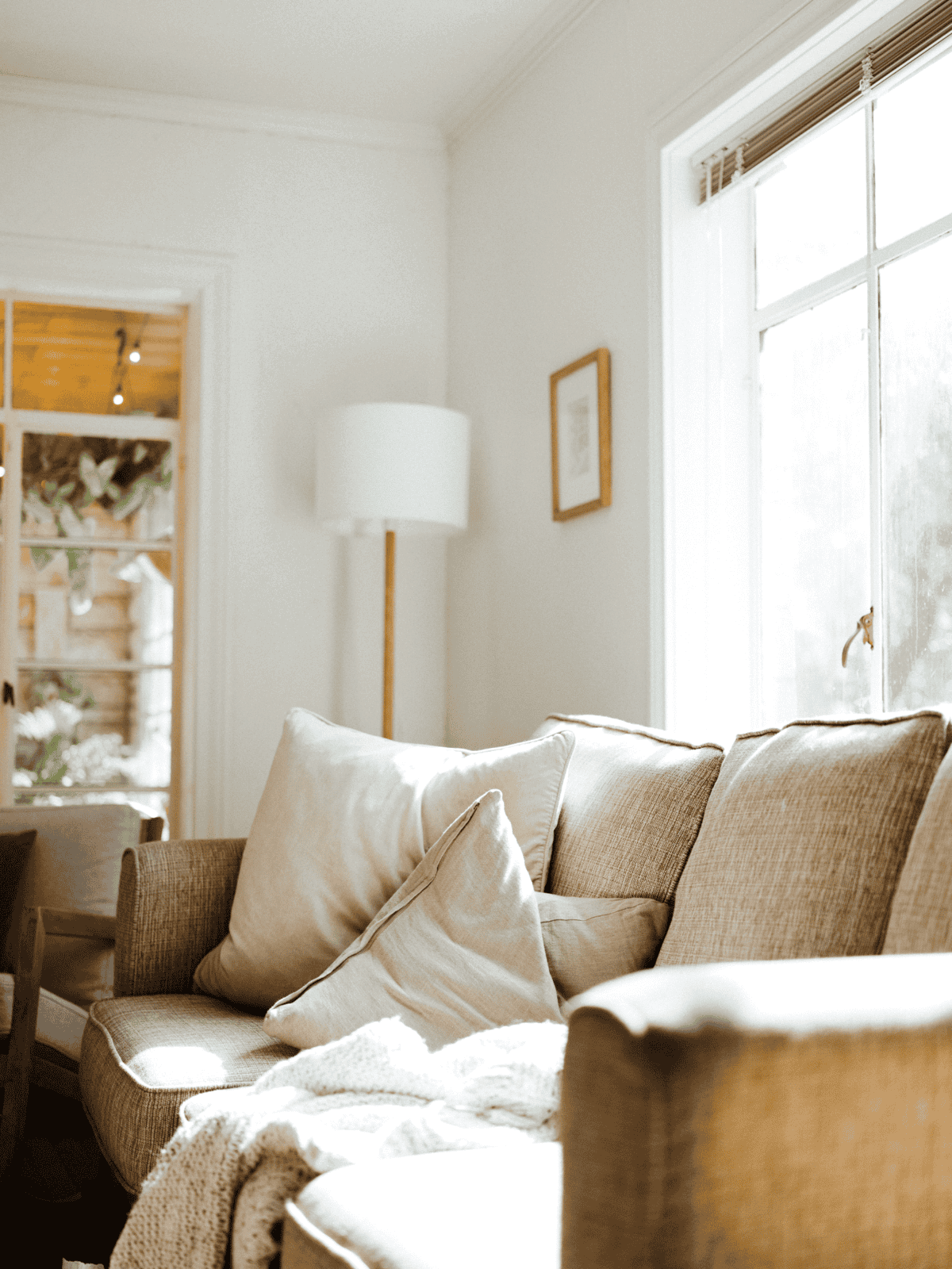 Comfortable beige sofa with pillows in a bright, inviting living room setting.