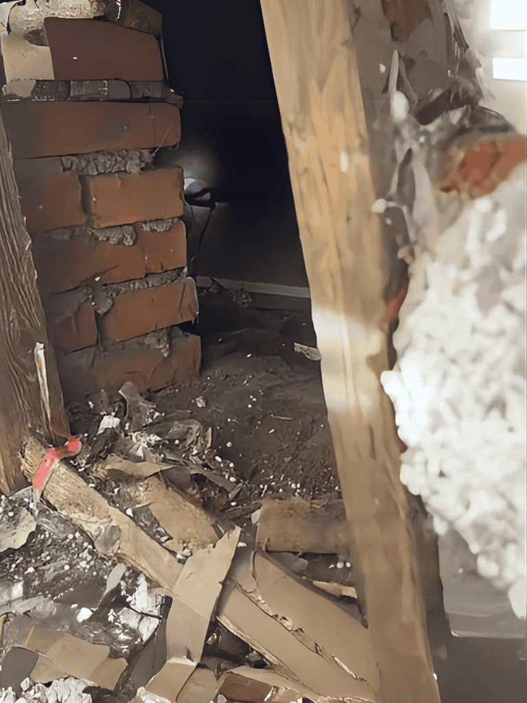 Fire damage with charred bricks and debris, showing a partially destroyed interior wall.