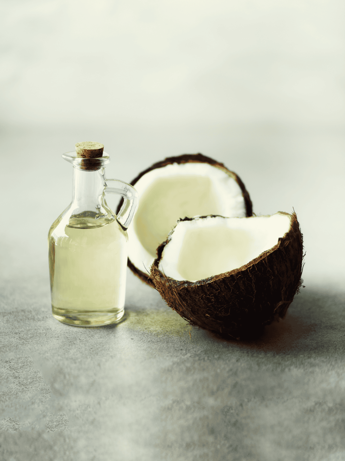 Healthy coconut oil in glass with fresh coconut halves for pet health and wellness.