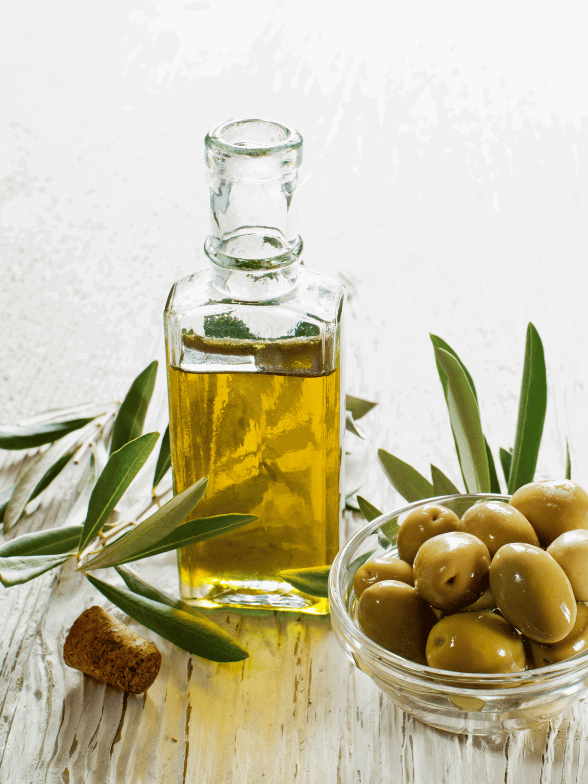 Healthy olive oil and fresh green olives with leaves for cooking and health benefits.