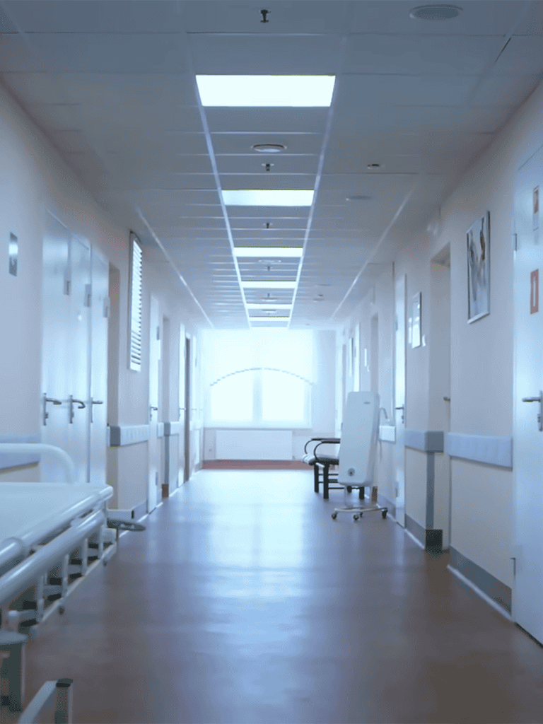 Bright hospital corridor with medical beds and equipment, sterile environment, healthcare setting.