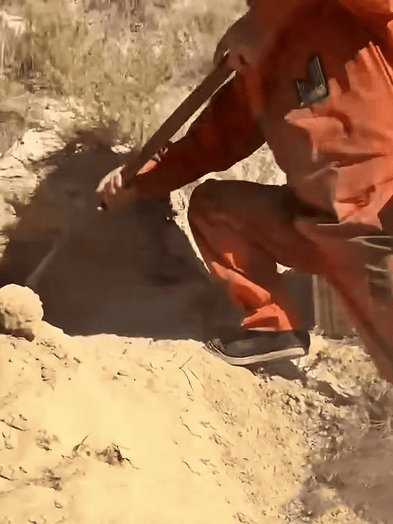 Close-up of a person digging in sandy ground with a tool, illustrating outdoor activity.