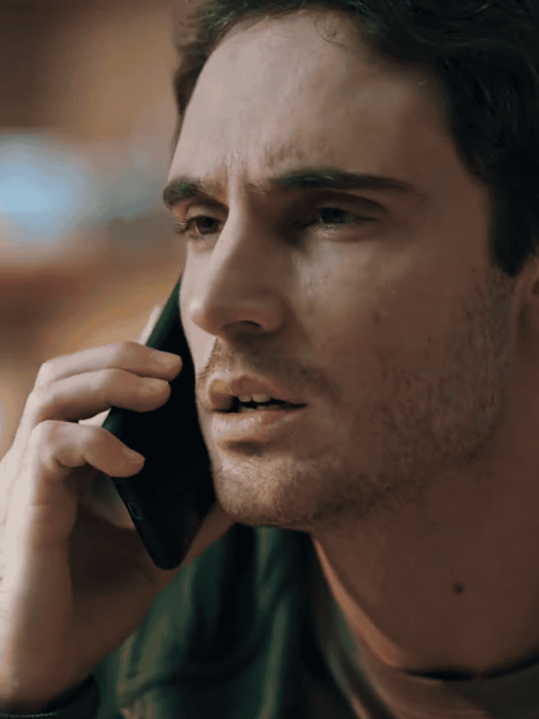 Alt text: Man on phone calls, serious expression, focused on conversation, outdoor background.