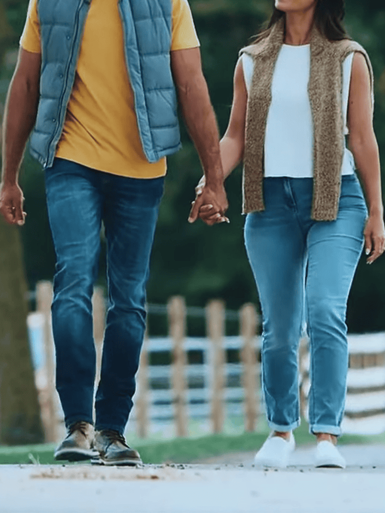 Close-up of a couple holding hands while walking outdoors on a sunny day.