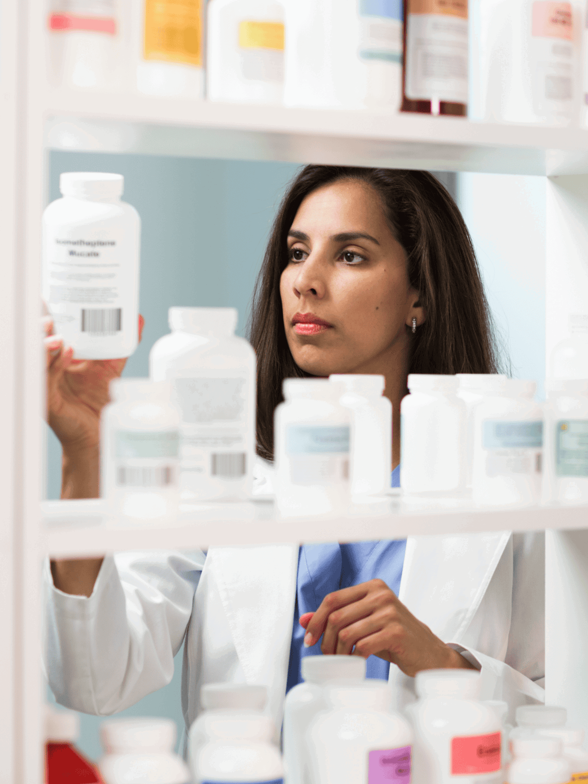 Pet medication bottles on shelves, veterinarian selecting medicine.