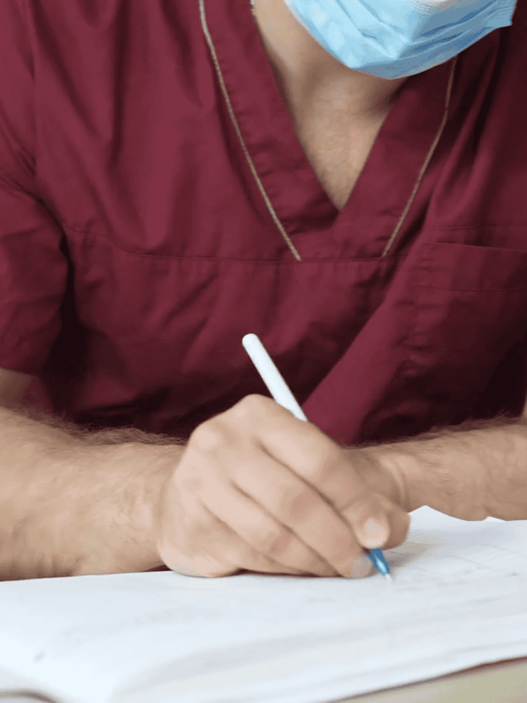 Veterinarian taking notes with pen, wearing medical scrubs and face mask, in a pet care or veterinary clinic.