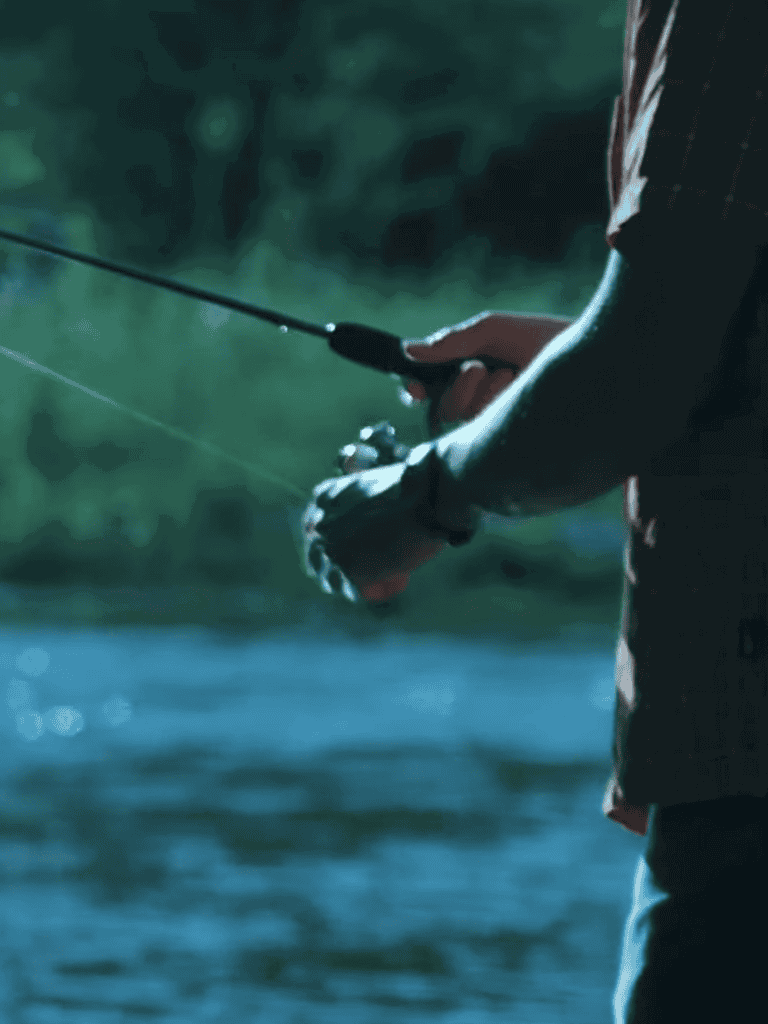 Fishing scene with a person holding a fishing rod near the water.