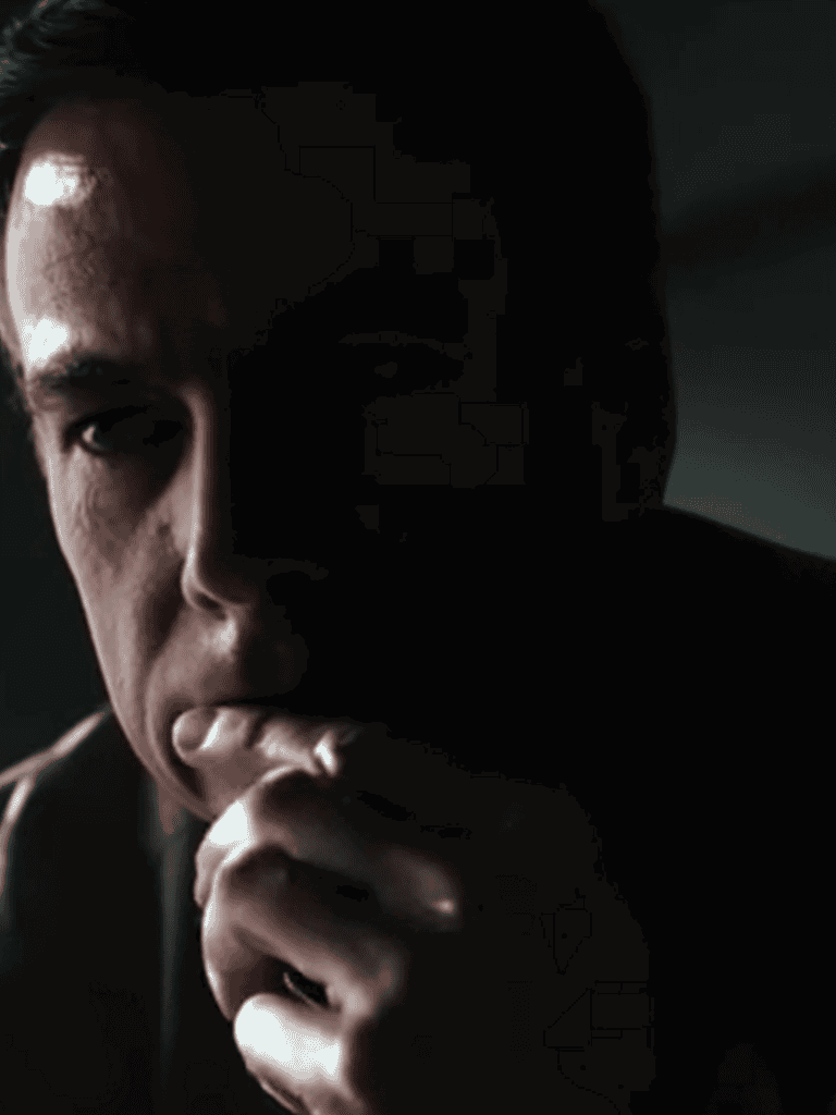 Close-up of a man deep in thought with hand near mouth, dark lighting, introspective mood.