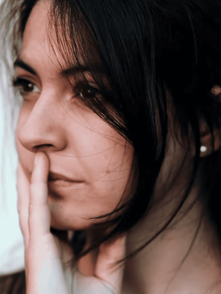 Close-up of woman placing finger on lips, quiet gesture.