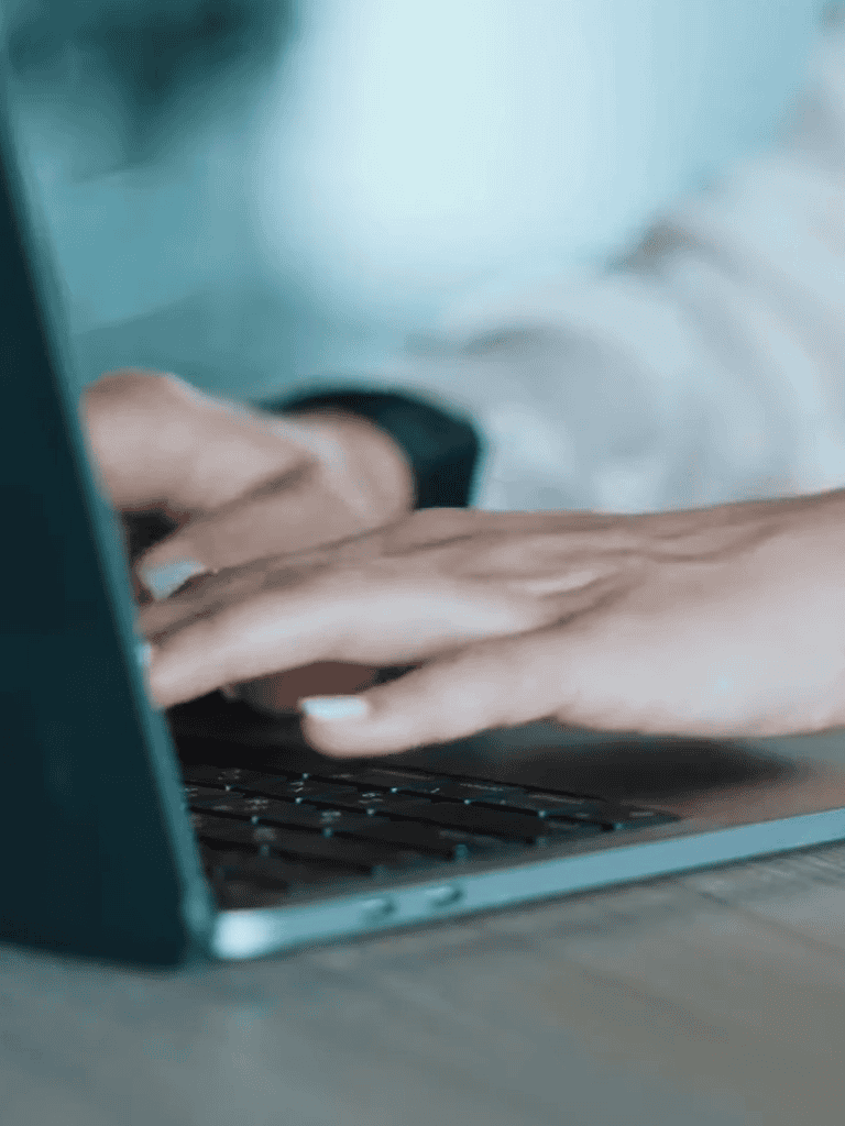 Close-up of hands typing on laptop, emphasizing pet-friendly remote work environment.