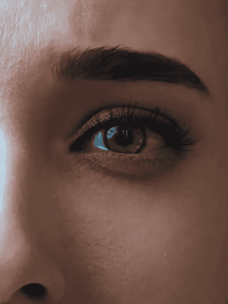 Close-up of a person's eye, highlighting detailed eyelashes, eyebrow, and smooth skin.