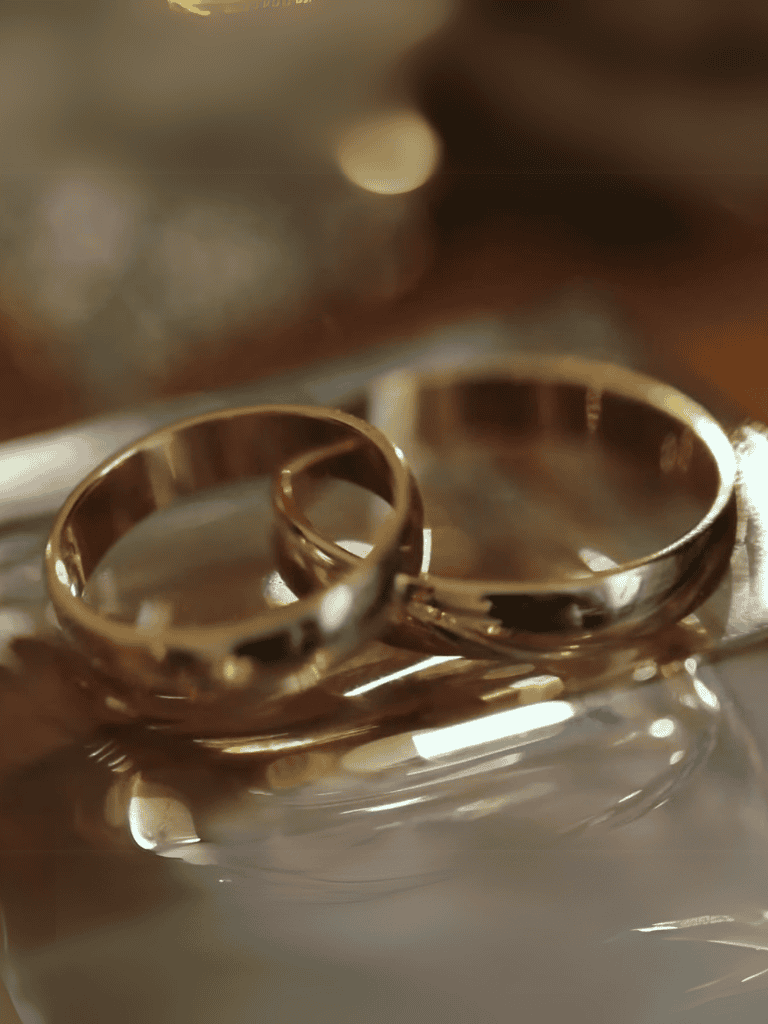 Close-up of two gold wedding rings on a reflective surface, symbolizing love and commitment.