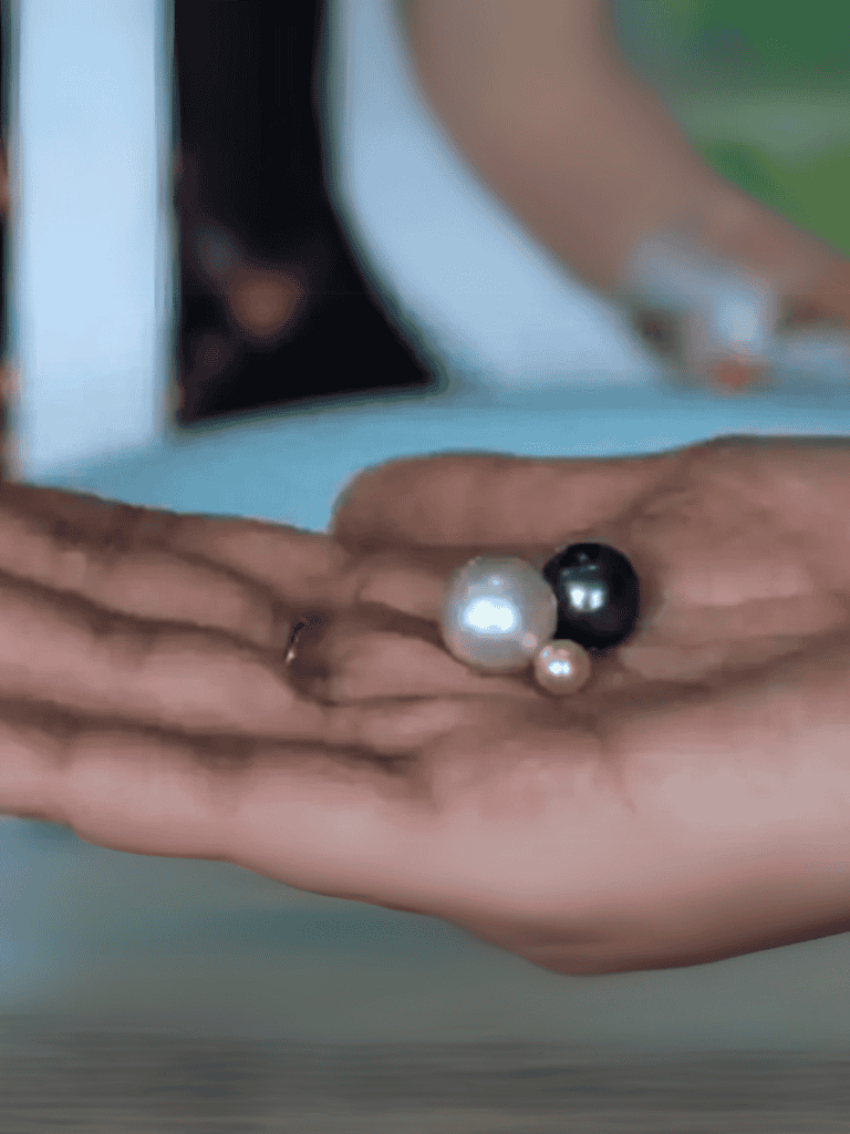 Close-up of hands wearing pearl jewelry with rings, showcasing fashionable accessories and elegant style.