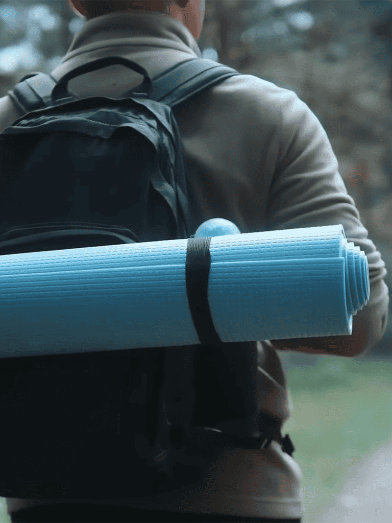 Backpacker with a blue yoga mat on shoulder, outdoor trekking, adventure travel gear.