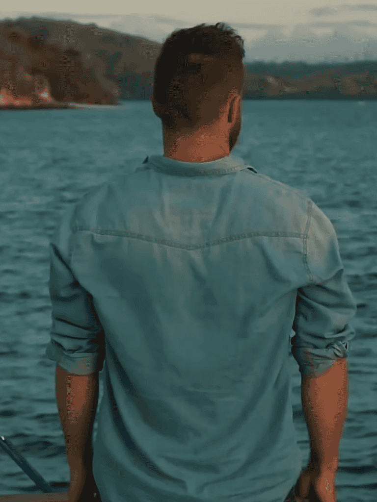 Man fishing by the lake at sunset.