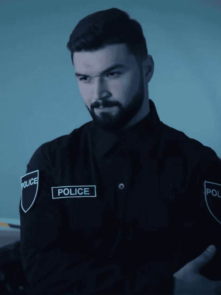 Police officer in uniform with "POLICE" patches, serious expression, close-up shot.