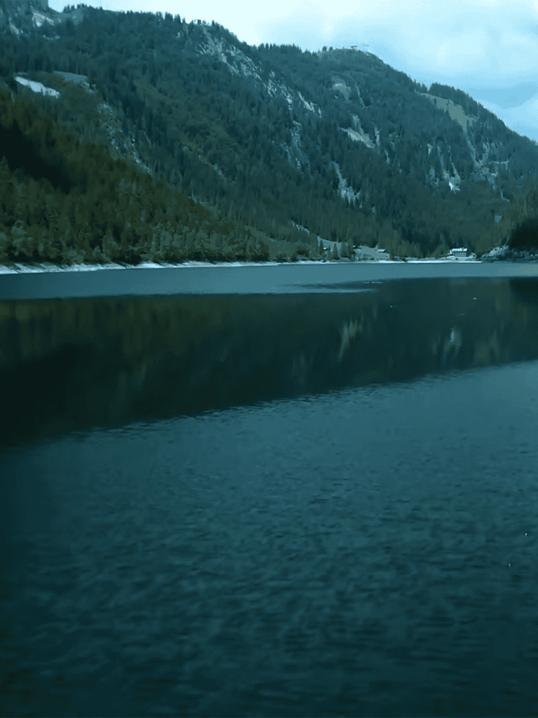 Peaceful mountain lake surrounded by lush forest and scenic mountain views.