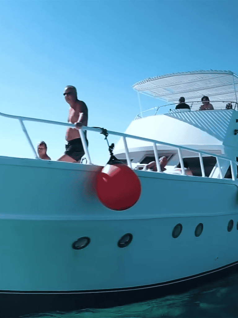 A group of friends enjoying a day on a luxury yacht, relaxing and having fun on the open sea under a clear blue sky.