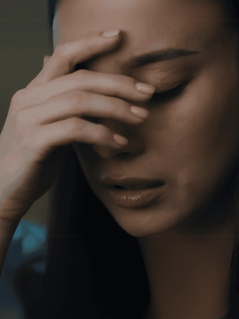 Anxious woman with hand on forehead, experiencing stress or emotional fatigue.
