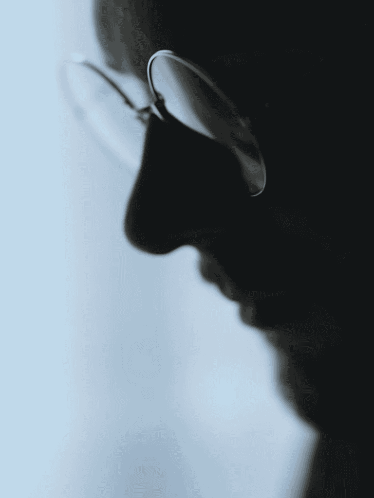 Close-up of a person's side profile wearing glasses, emphasizing their contemplative expression.